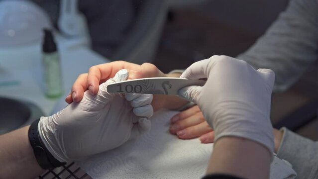 Beautician wearing latex gloves performs manicure