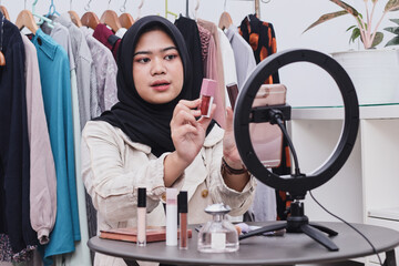 Muslim asian female beauty social media influencer livestream marketing cosmetics a make up tutorial via smartphone.