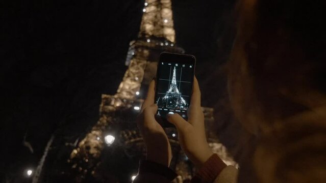 Woman taking pictures of the Eiffel Tower in Paris, France