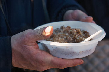 Plate with food in the hands of a man outdoors close-up. The concept of hunger. Selective focus.
