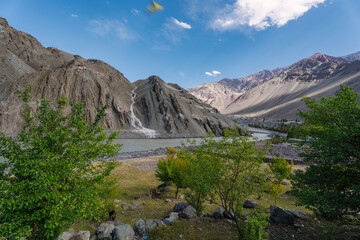 beautiful landscape with green trees and blue sky, mountains in the background at Ladakh, in the Indian Himalayas.