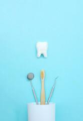 Dental tooth model with metal medical dentistry equipment tools - teeth dentist mouth mirror, toothbrush in white glass