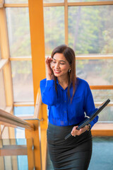 Indian Corporate woman holding laptop in hand and giving smile expression at office.