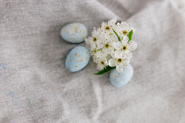 Beautiful spring background with easter pastel eggs and flowering branch on a linen gray towel. Easter card. Blue eggs and white flowers. Mock up