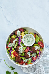 Falafel salad with avocado, tomato and tahini dressing.