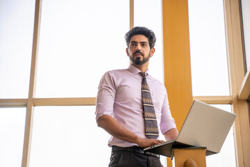 Young indian manager or employee using laptop at office