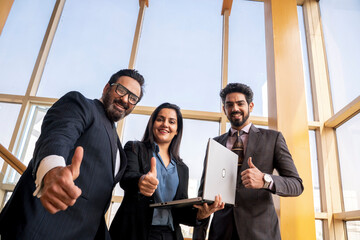 Indian businesspeople showing thumps up at office.