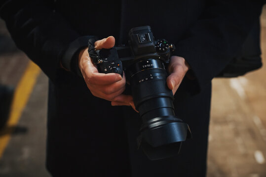 photographer holds a modern mirrorless camera in hands close-up