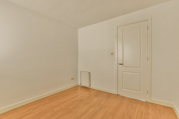 an empty room with white walls and wood flooring on the right, there is a door that leads to...