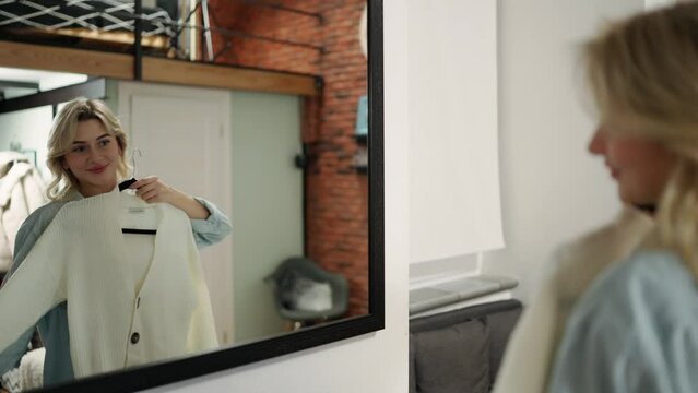Blondy chooses clothes in the wardrobe at home. A woman tries on a white jacket