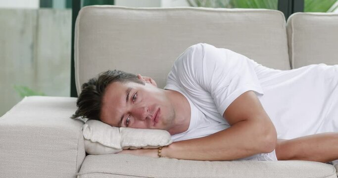 Young man suffers from apathy, mental health problems and depression. Portrait of a young man lying on the couch in an apathetic state and suffering from obsessive bad thoughts and depression
