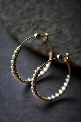 big round gold earrings with white pearls against gray background