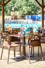 Outdoor street cafe with designer plastic furniture in aqua park on sunny summer day. Table and chairs with transparent backs under cover