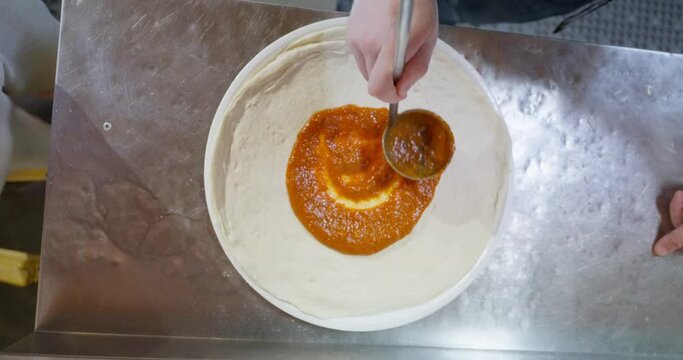 Making pizza from scratch with pizza sauce, cheese and sausage. mobile phone video, vertical video. Close up of hands making pizza.