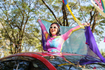 Happy Asian woman support LGBT pride parade in car. with Rainbow of LGBTQ or LGBTQIA.