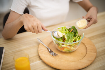 Happy beautiful Asian woman eating healthy food with vegan.salad in the kitchen at home.