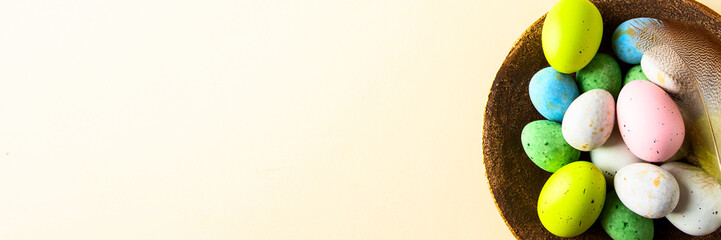 Colorful Easter eggs and feather on beige background .Flat lay composition for banner.