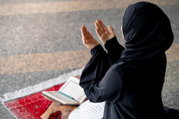 The image of an Asian Muslim woman in the Islamic religion in hijab in black color. She was praying...