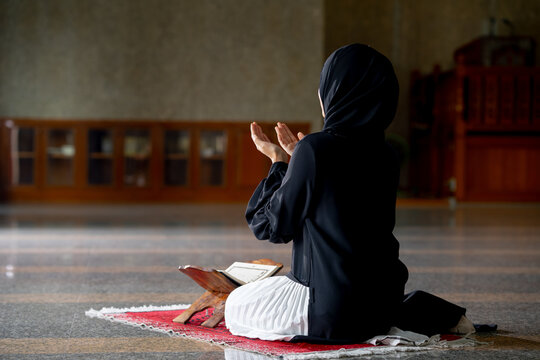 The image of an Asian Muslim woman in the Islamic religion in hijab in black color. She was praying in a beautiful mosque out of respect for God.