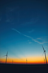 Windmill farm park in silhouettes with colorful sky.