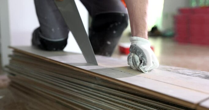 Working master cutting piece of laminate using hand saw