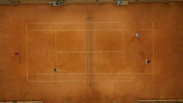 Aerial top-down shot of a doubles tennis match being played on a clay court in Mendoza