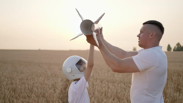 Father man son boy child teenager playing aviator cosmonaut with toy rocket in sunset field. Kid big dream flying astronaut space, Concept childhood Parent dad having fun happy family together summer 