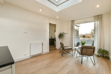a living room with hardwood flooring and skylights on the ceiling, there are two chairs facing one...