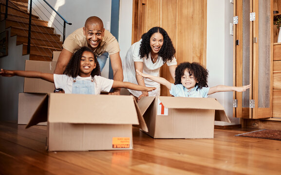 Children in boxes while moving into a new home with their parents playing in a silly, goofy and fun mood. Happy, smile and family being playful together in their modern house, apartment or property.