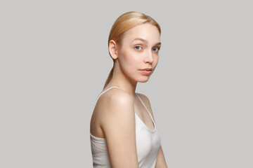 Fresh blonde woman in white top isolated on grey background. Beauty, cosmetics, skincare, glamour