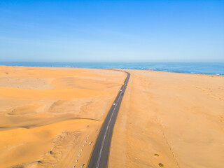 Aerial top view of street road with Namib Desert Safari, sand dune, coast sea in Namibia, South Africa. Natural landscape background at sunset. Famous tourist attraction. Sand in Grand Canyon