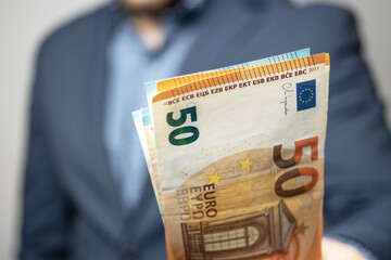 Well dressed man holding in the hand or giving bunch of money, euro banknotes, European Union paper currency