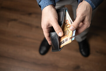 Well dressed man puts a bunch of money in his leather wallet, euro banknotes, the paper currency of the European Union