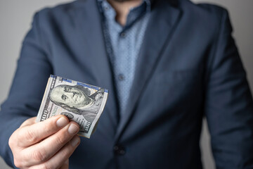 Well dressed man holding in the hand or giving bunch of money, dollar banknotes, US paper currency