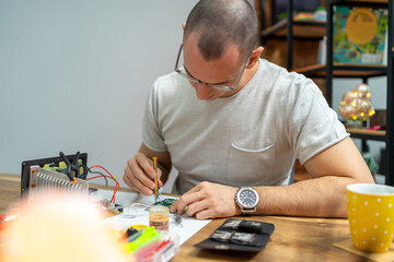 The young master electronics engineer checks, repairs and finishes the motherboard he was given to...