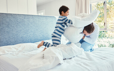 Playing, dad and son in pillow fight on bed, fun quality time and man bonding with child at home....