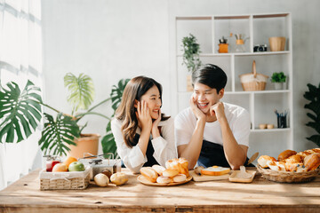 Image of newlywed couple cooking at home. Asia young couple cooking together with Bread and fruit...