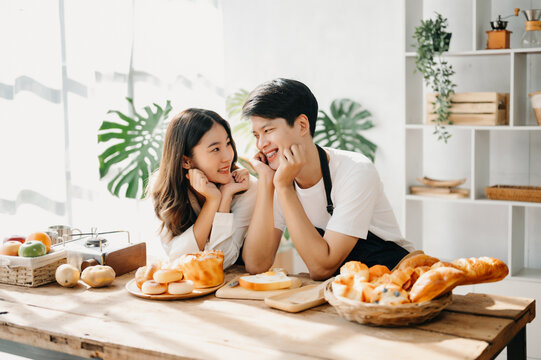 Image of newlywed couple cooking at home. Asia young couple cooking together with Bread and fruit in cozy kitchen