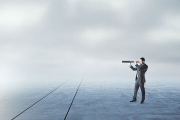 Businessman with telescope looking into the distance on abstract dull sky and ground background with mock up place.
