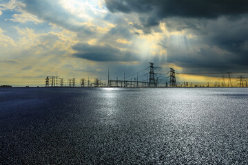 Asphalt road ground and high voltage power towers on cloudy day