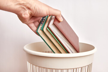 A used business notebook is thrown into the trash. Paper disposal and recycling.