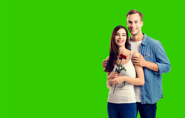 Love, relationship, dating, flirting, romantic concept - portrait of happy smiling hugging couple with flower, isolated green chroma key background.