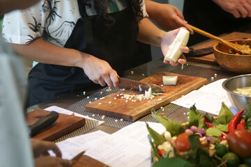 Adult students learning recipe and preparing meal in cooking class