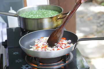 Preparation of vegetables on the stove, sauting onion and boiling green beans