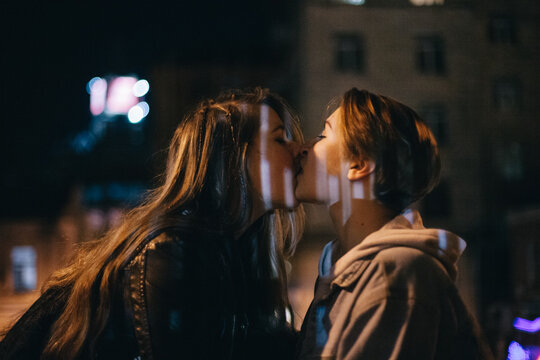 Lesbian couple kissing in city at night