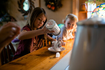 Young girl adding lots of sugar to cup of tea