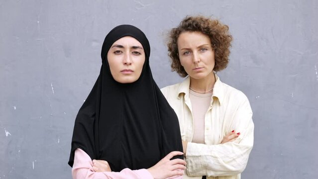 Portrait, Feminist women stand with hands folded on chests and staring seriously into camera. Two feminist women activists fighting for women's rights regardless of their religion, race, social status