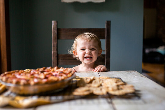 Happy girl sitting at table wanting some fresh warm apple pie
