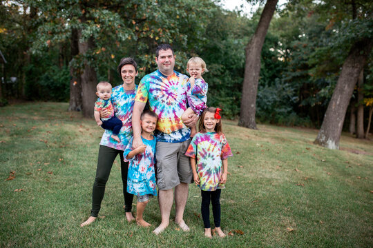 Fun full family portrait wearing colorful tie dye shirts