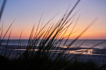 beautiful sunset on the sea with a pavilion in the foregroundSunset on the beach with grass and sand dunes in the foregrou